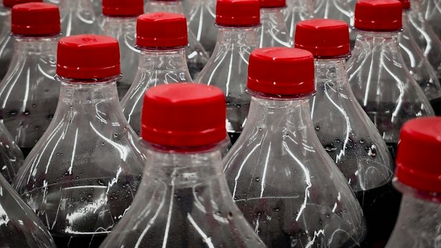Botellas de plástico con tapa roja alineadas en una línea de producción